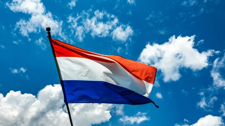 Bandera de Países Bajos ondeando frente a un cielo azul - Facialix
